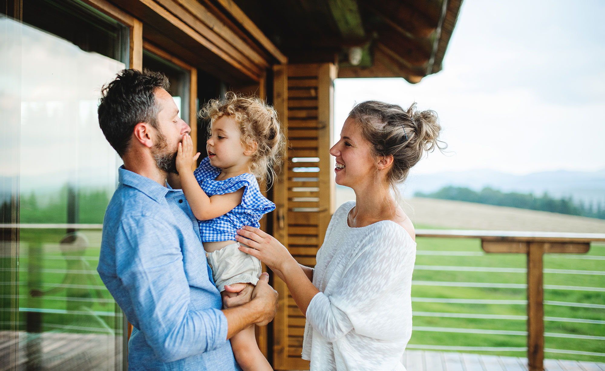 family-with-small-daughter-on-patio-of-wooden-cabi-2023-11-27-05-10-48-utc.jpg